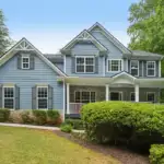 Blue-gray two-story home with a front lawn and mature trees